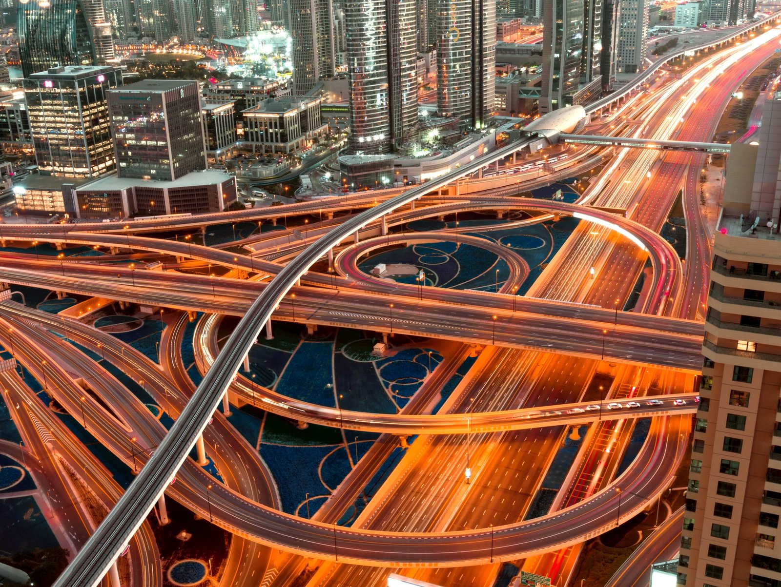 A high angle shot of an illuminated  highway with multilevel intersections in a megapolis at night